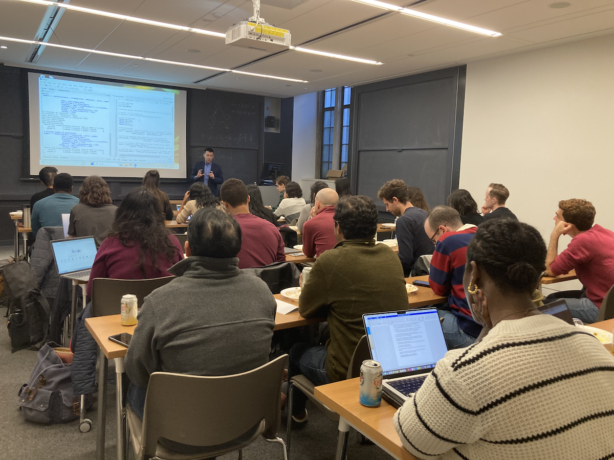 A professor shows code in the RStudio console to a full room of attendees